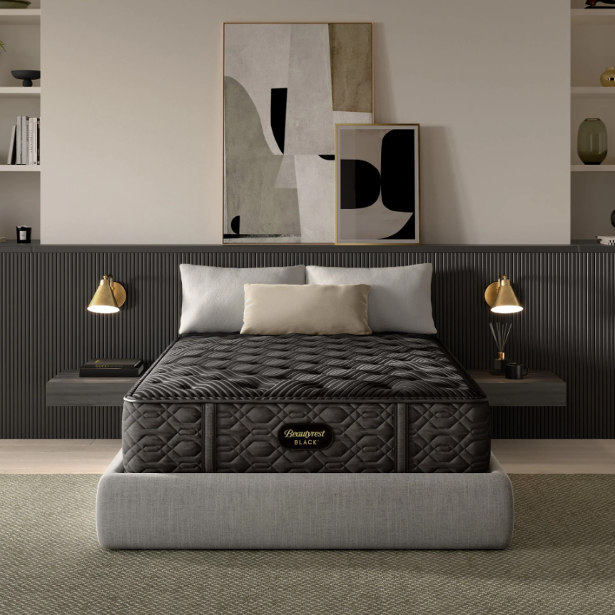 Black mattress on a gray bed frame in a modern bedroom setting with abstract art and lamps.