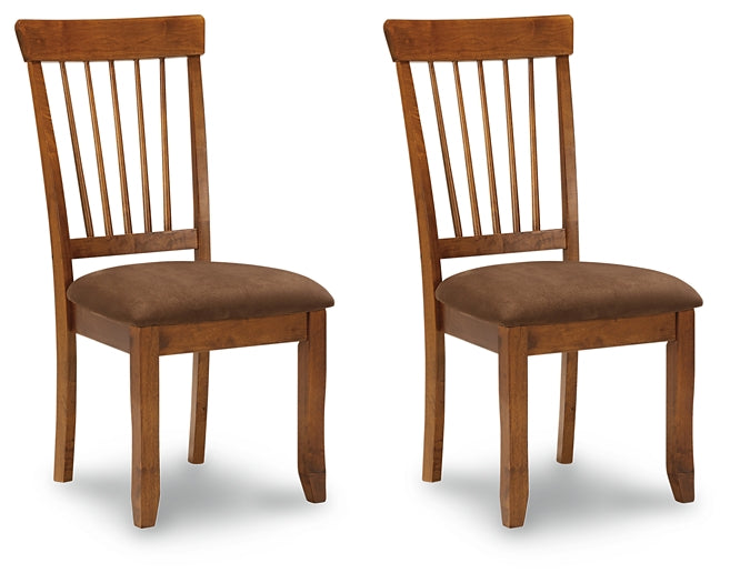 Two wooden chairs with brown cushioned seats on a white background