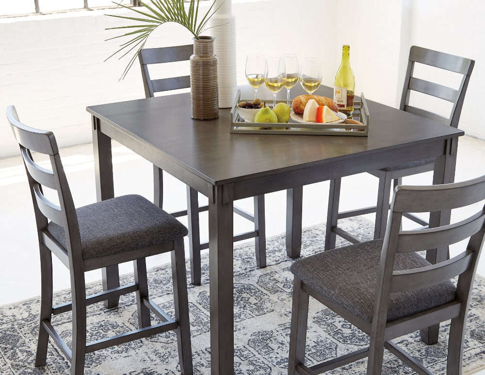 Dining table set with chairs and a decorative tray on a patterned rug.