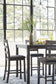 Dining room with a table and chairs near large windows.