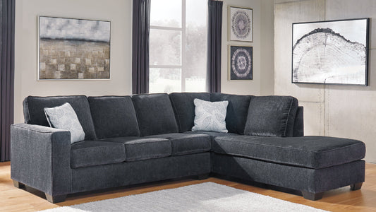 Gray sectional sofa in a living room with a white rug and framed artwork on the walls.