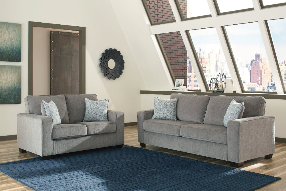 Gray sofa set in a living room with large windows and cityscape view.
