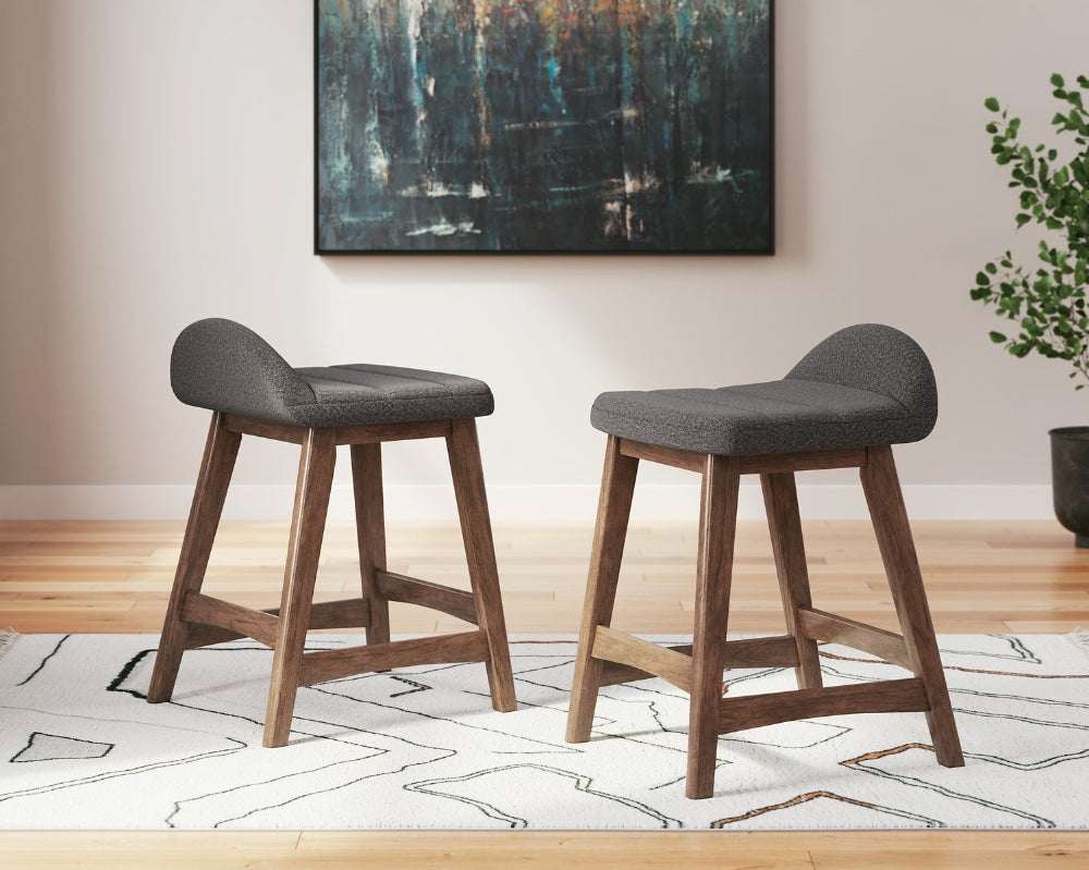 2 dark gray upholstered stools on a white rug with an abstract painting on the wall