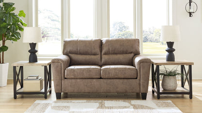 Brown loveseat in a living room with tables, lamps, and decor.