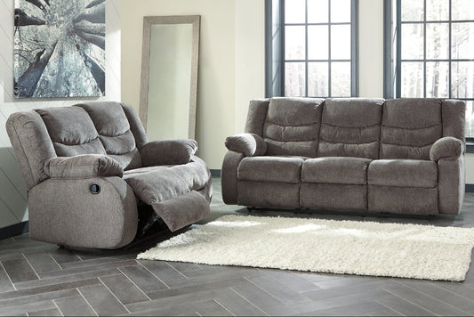 Gray reclining sofa set in a living room with large windows.