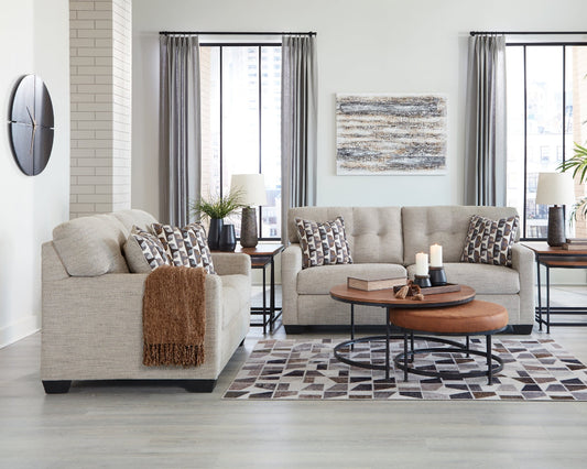 Modern living room with beige sofa and loveseat, a coffee table, and decorative elements.