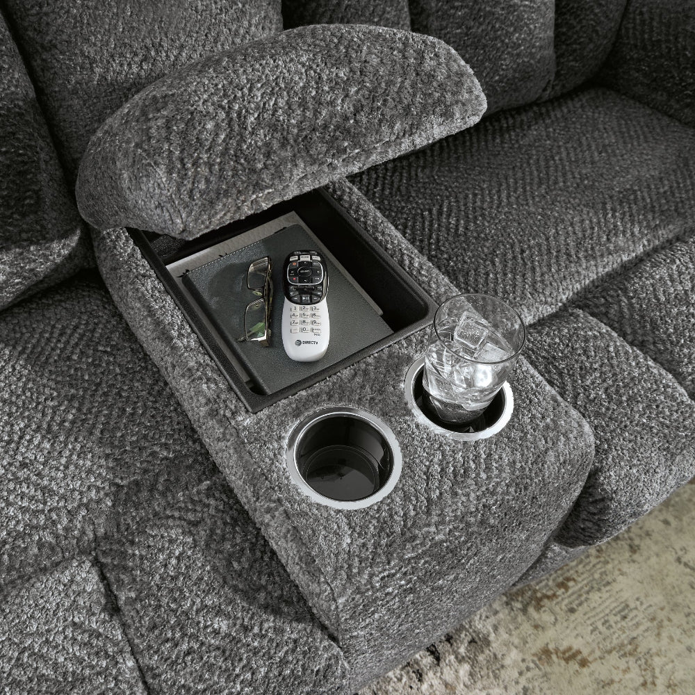Gray textured loveseat with cup holder and tray containing a phone, glasses, and a glass of water.