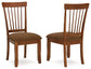 Two wooden chairs with brown cushioned seats on a white background
