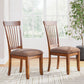 Two wooden chairs with brown cushioned seats in a room with a plant and window.