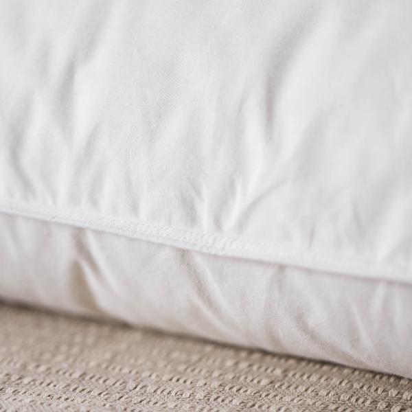 Close-up of a white quilted mattress pad on a textured surface.